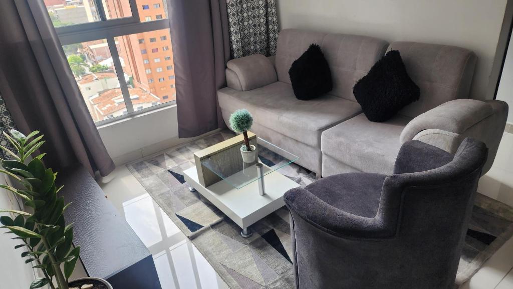 un soggiorno con divano, 2 sedie e tavolo di Apartamento central a Medellín