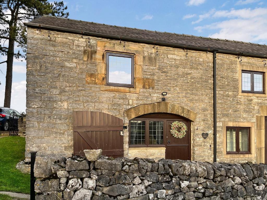 an old stone building with a garage and a stone wall at Sienna Cottage - W7764 in Monyash