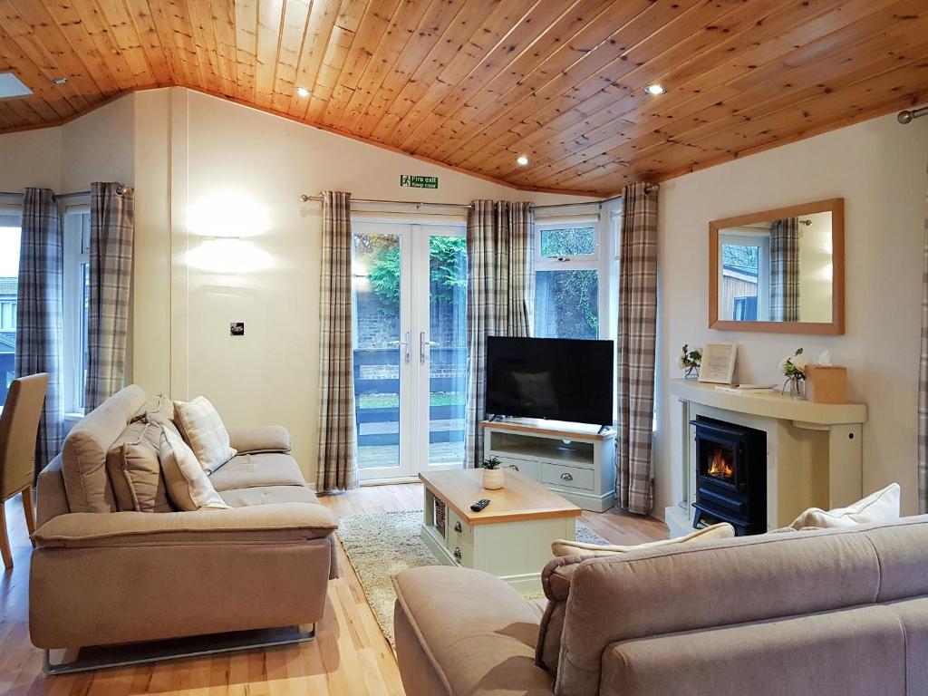 a living room with couches and a tv and a fireplace at Kingfisher Lodge - Uk46046 in Balloch