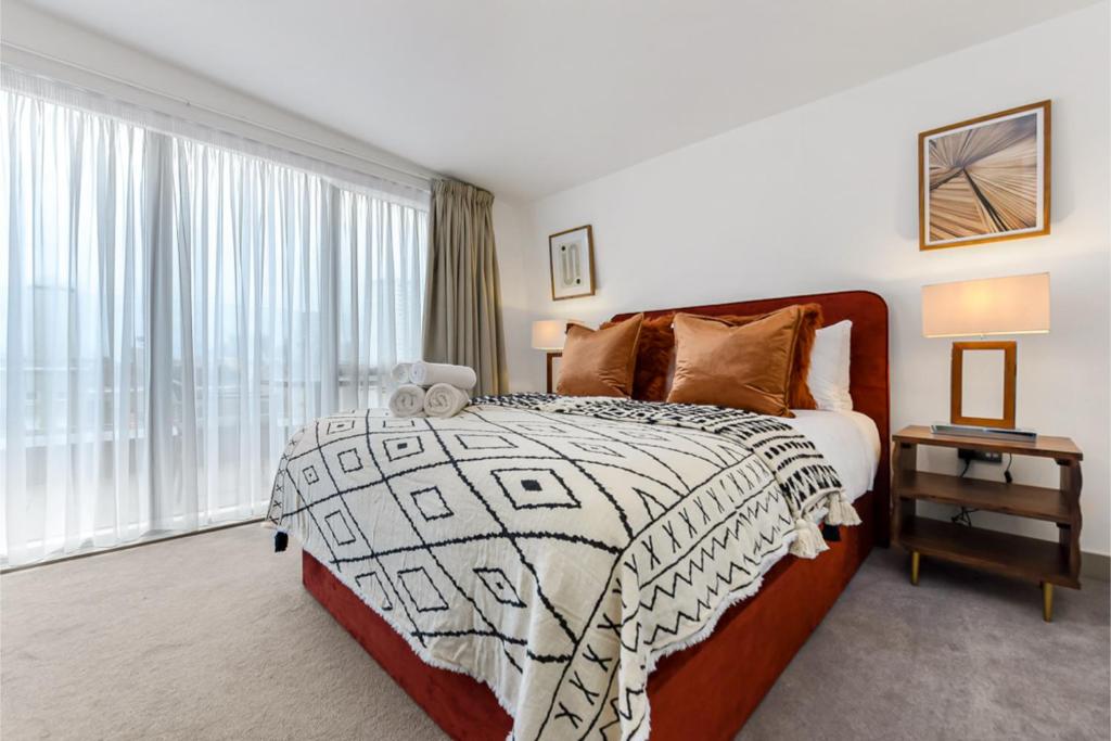 - une chambre avec un lit et une grande fenêtre dans l'établissement Earthy Elegance: Nature Inspired Flat in Prime Location, à Londres