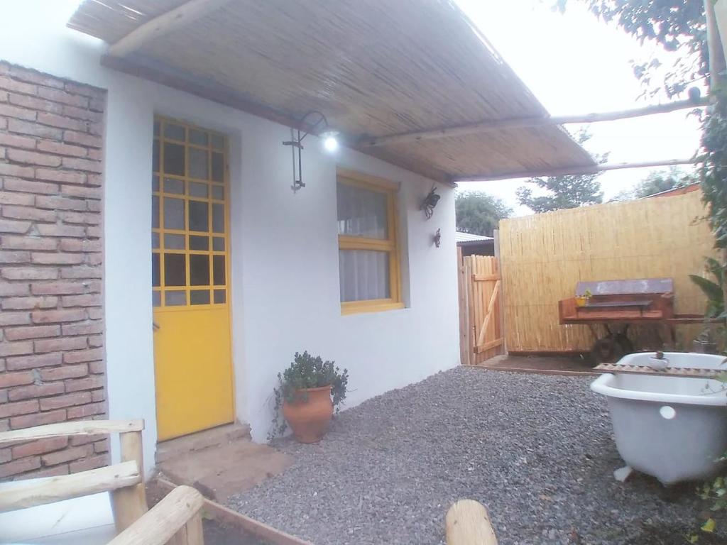uma casa branca com uma porta amarela e uma cerca em CASITA PINTORESCA EN LAS SIERRAS Y LAGO em San Roque