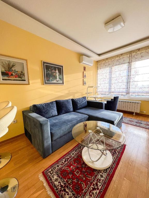 a living room with a blue couch and a table at Mega Lux Apartment in Vračar (historical)