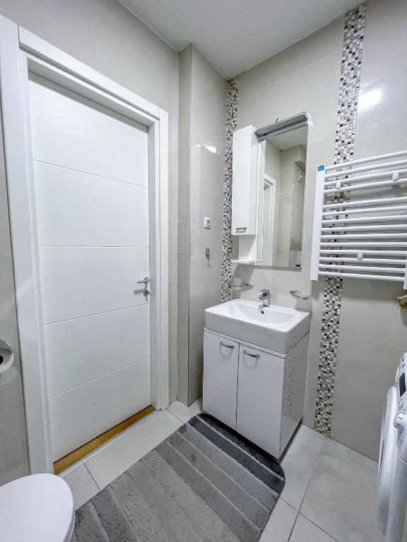 a white bathroom with a toilet and a sink at Mega Lux Apartment in Vračar (historical)