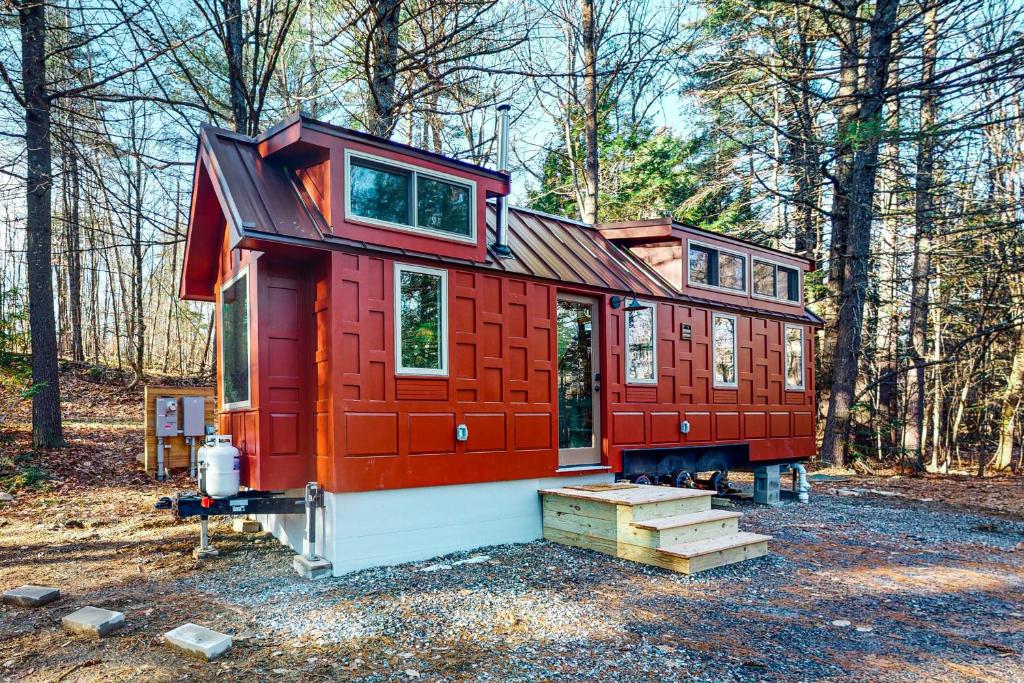 a red tiny house sitting in the woods at Thainy House in Gardiner