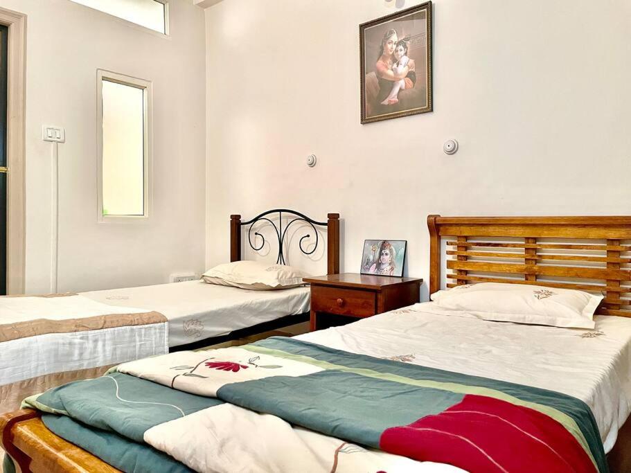 um quarto com 2 camas, uma mesa e um espelho em Shanthi Home Stay em Puttaparthi