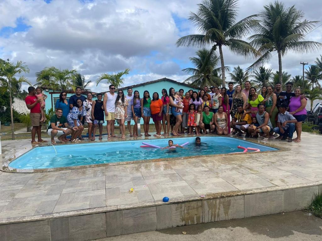 a group of people standing around a swimming pool at Chácara coqueiral in Estância