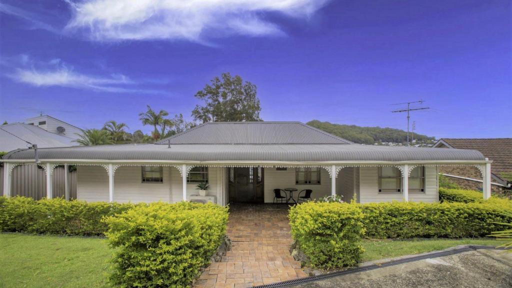 a white house with a porch and bushes at 'Fair View On Daleys' by HolidayCo in Daleys Point
