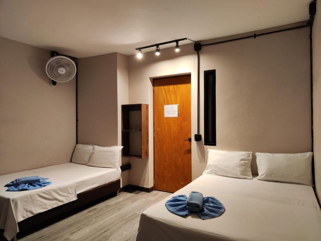 um quarto com duas camas e uma porta em Hostal Machu Picchu Medellín em Medellín