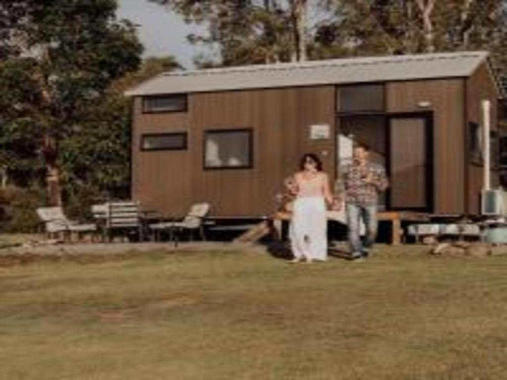 a man and a woman standing in front of a tiny house at Hill Creek Tiny House in Perwillowen