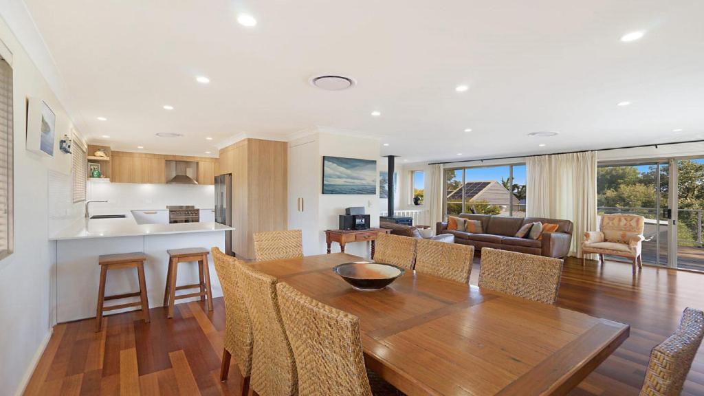 a kitchen and living room with a wooden table and chairs at 'Spacious Family Retreat' by HolidayCo in Killcare