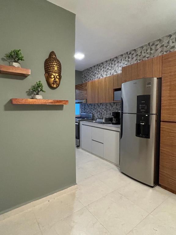 a kitchen with a stainless steel refrigerator and a mask on the wall at Kobikhome in Cancún