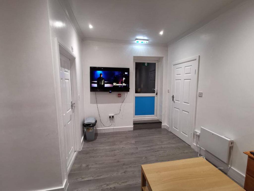 a hallway with a flat screen tv on a white wall at Studio Apartment near Luton Airport and Luton Central in Luton