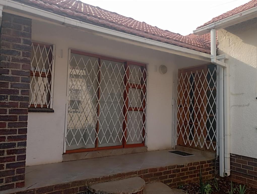 uma casa com uma porta fechada com dois bancos em Yakhe Self-catering Accommodation in Edenvale Johannesburg em Edenvale