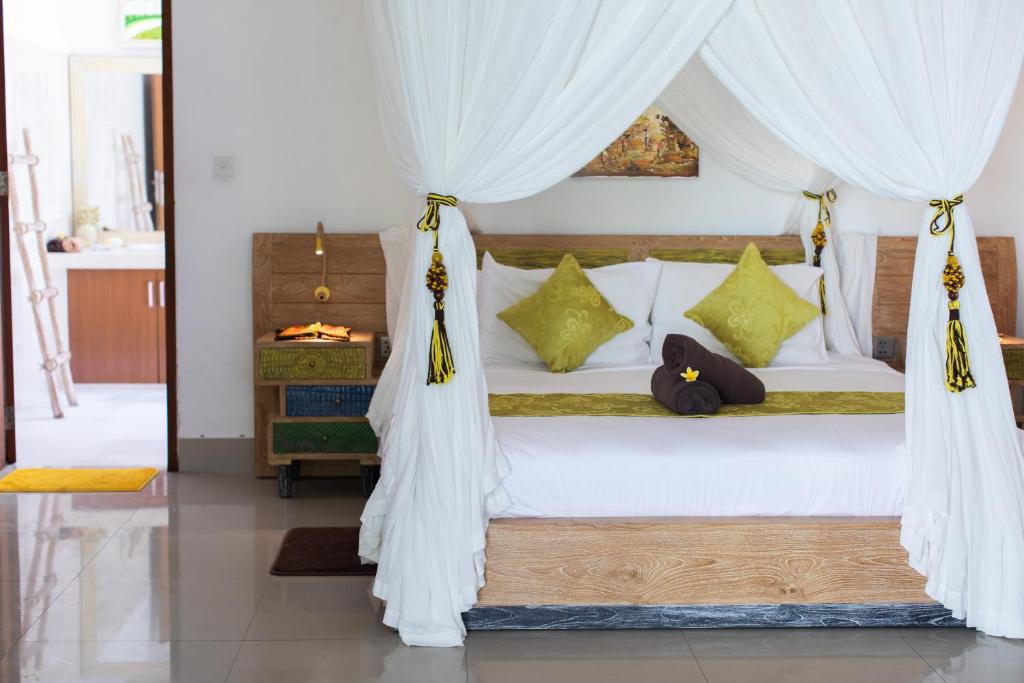 a bedroom with a white canopy bed with yellow pillows at MasBro ART Villas in Seminyak