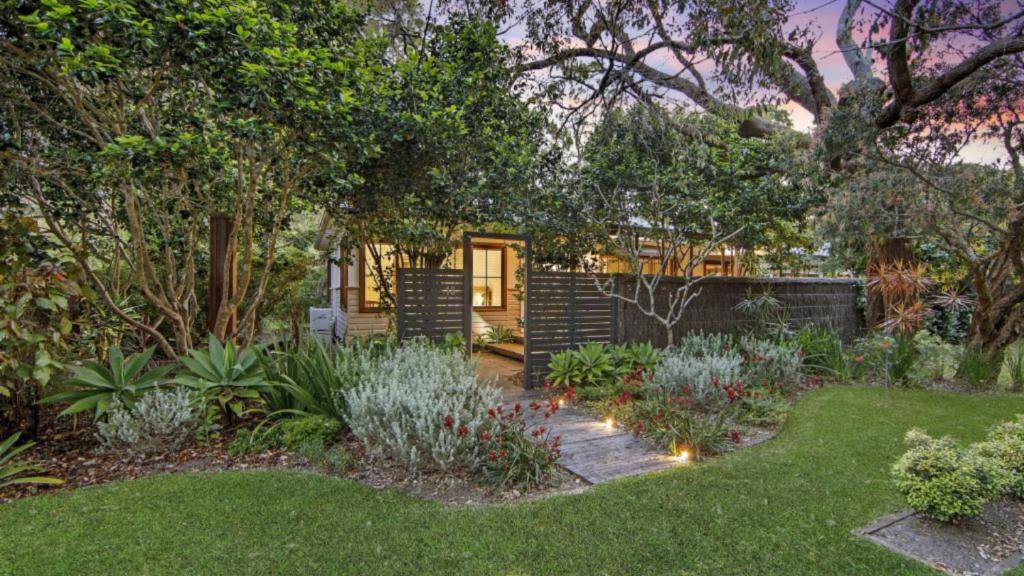 a backyard with a garden with plants and a fence at Pearl Beach Quarterdeck in Pearl Beach