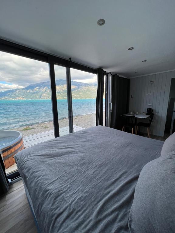 a bedroom with a bed and a view of the ocean at Chelenko Lodge in Puerto Tranquilo