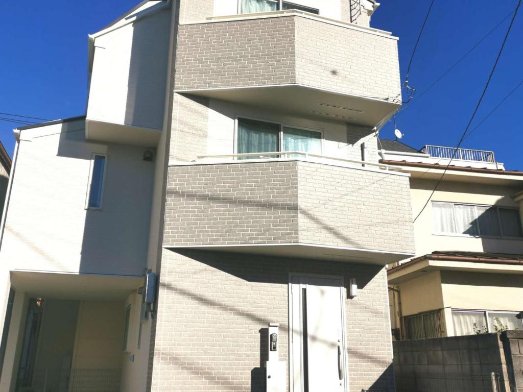 ein hohes weißes Backsteingebäude mit einem Balkon in der Unterkunft KIK HOUSE-Self Check in- Will send room number and password in Tokio