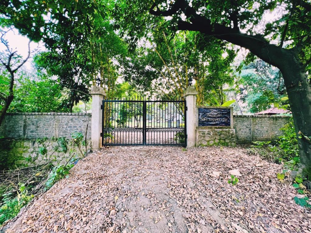 a gate with a tree in front of a fence at NB Nature Stay in Navi Mumbai