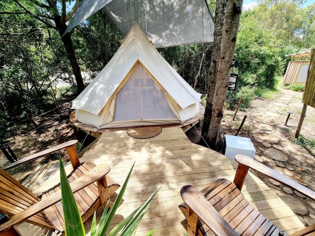 a tent sitting on a wooden deck with chairs at Zen Valley Glamping in Plettenberg Bay