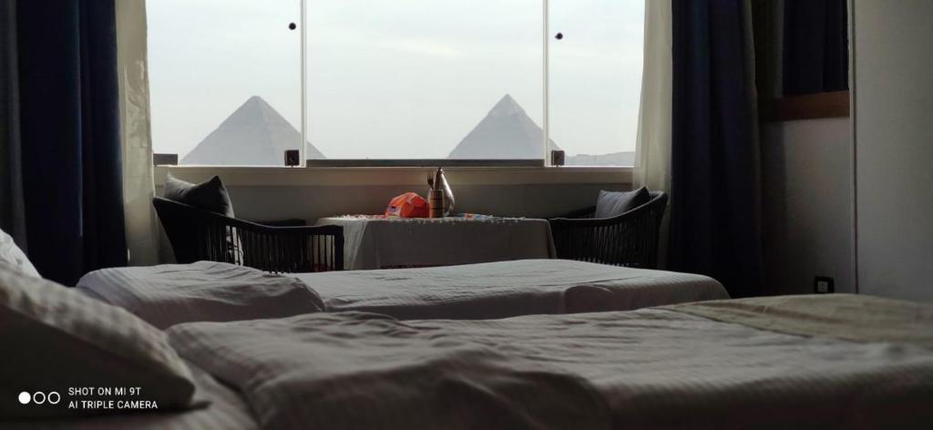 a room with two beds and a window with pyramids at توت كينج بيراميدز فيو in Cairo