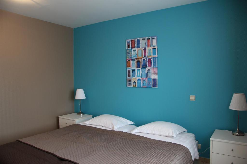 1 dormitorio con una pared azul, 1 cama y 2 lámparas en Relais Charlemagne Sca, en Herve