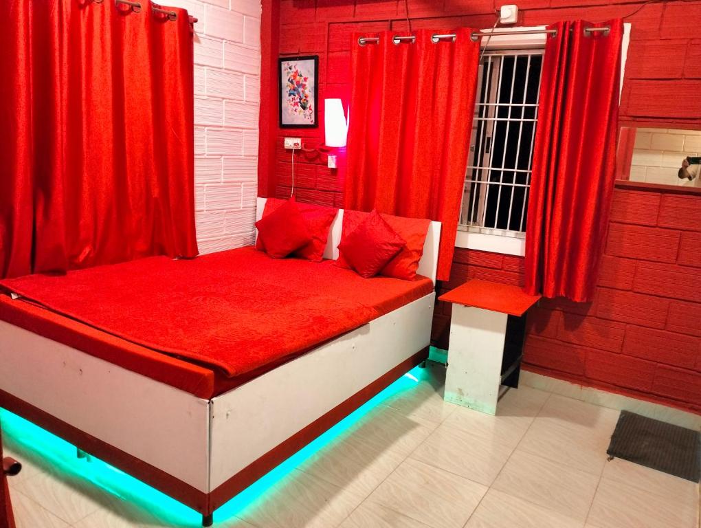 um quarto vermelho com uma cama com cortinas vermelhas em Greenland gokarna Ac and Non Ac em Gokarna