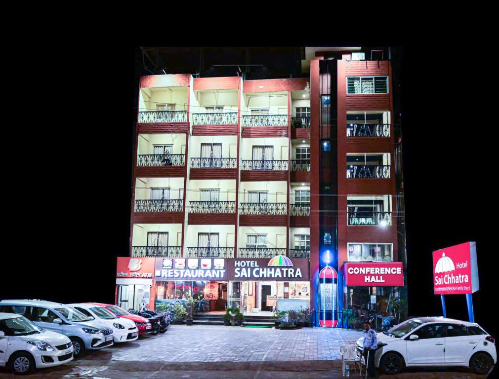 un edificio alto con coches estacionados frente a él en Hotel Sai Chhatra, en Shirdi