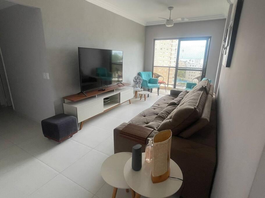 a living room with a couch and a flat screen tv at Apartamento recém reformado, com ar condicionado e perto da praia! in Guarujá
