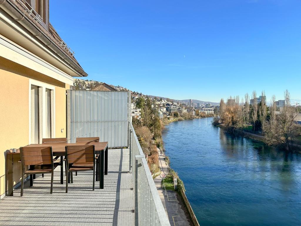 balcón con mesa y sillas junto a un río en STAYY The River - contactless check-in, en Zúrich