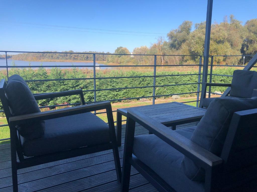 蒂薩菲賴德的住宿－OpusTisza7 Apartman，甲板上配有两把椅子和一张桌子,享有田野的景色