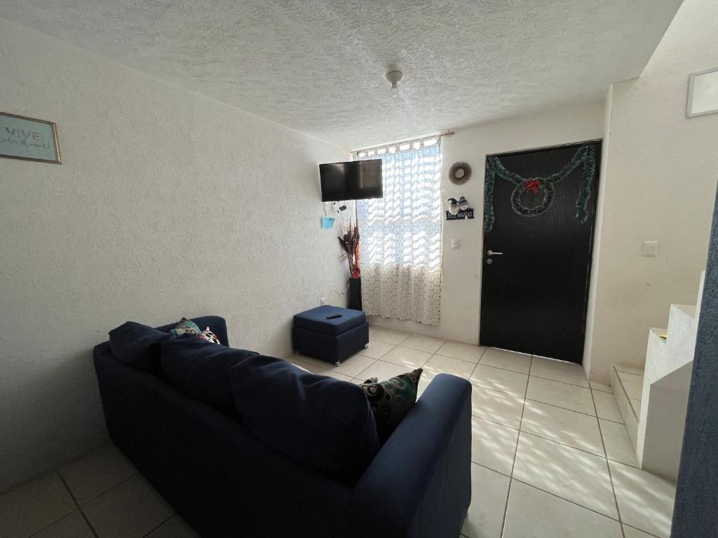 sala de estar con sofá azul y puerta negra en Casa no en servicio, en Guadalajara
