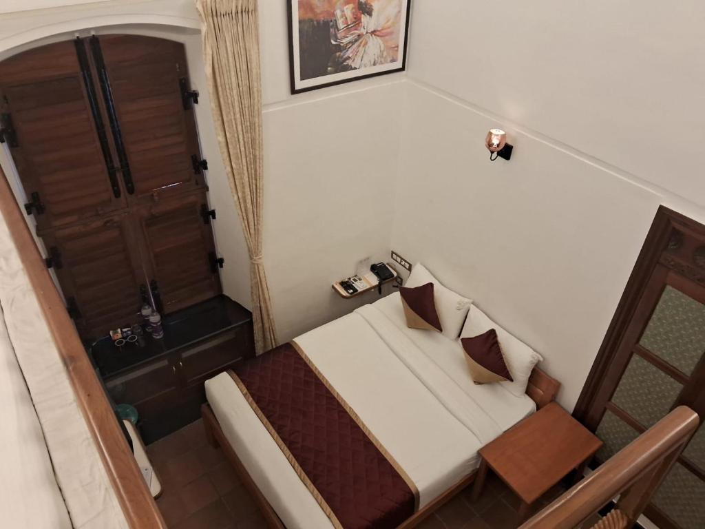a small bedroom with a bed and a wooden door at Pearl bell Villa in Puducherry