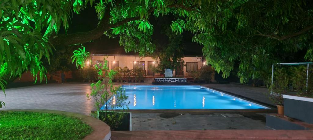 a swimming pool in a yard at night at Ashoka Lawns and Resort in Alibaug