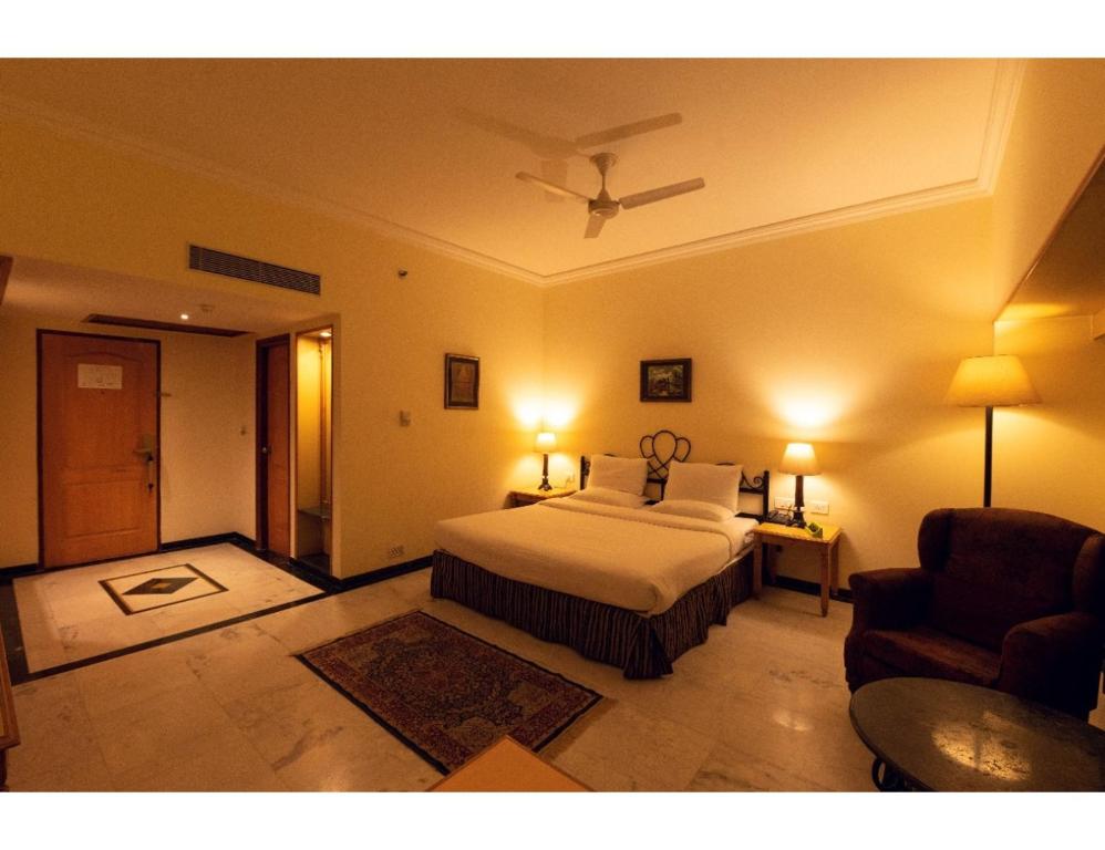 een slaapkamer met een bed, een bank en een stoel bij A Hotel, Ludhiana in Ludhiana