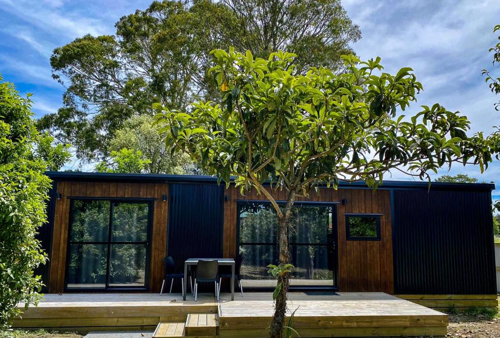a house with a table and chairs and a tree at Havelock North Holiday Park in Havelock North