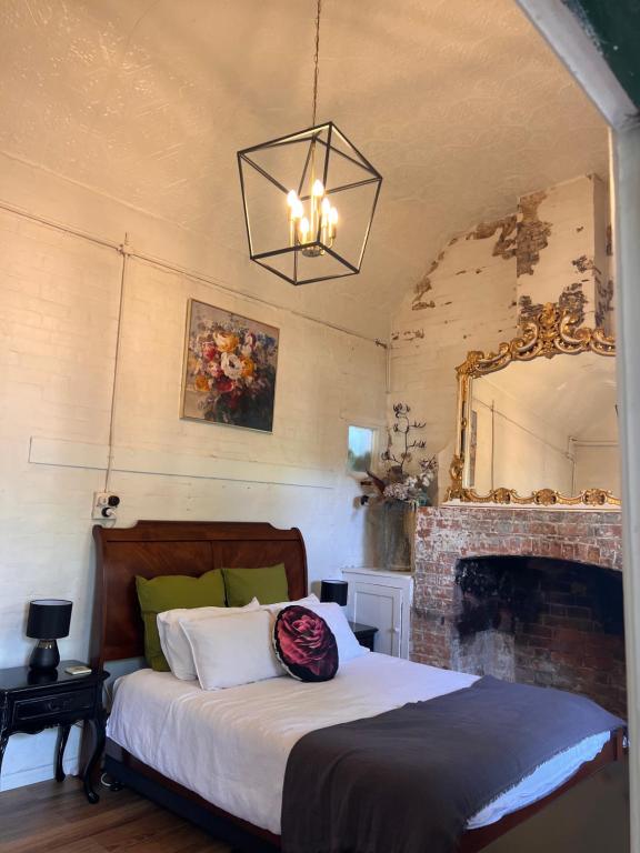 巴瑟斯特的住宿－The Tamarisks at Rosevale，一间卧室配有一张带壁炉和镜子的床