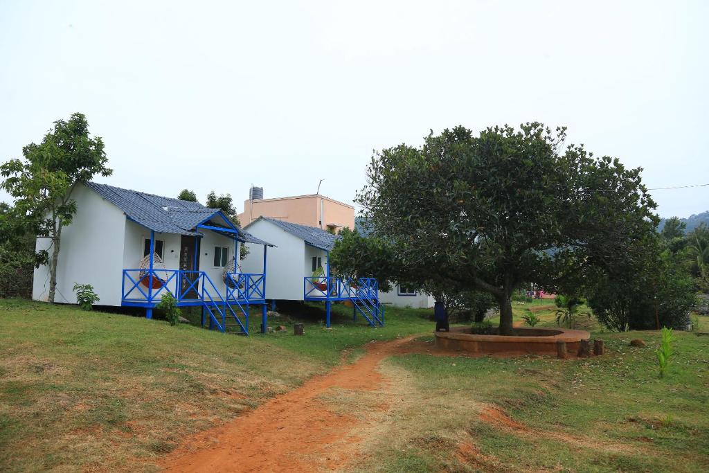 a white house with blue gates and a tree at Rainbow Residency in Yelagiri