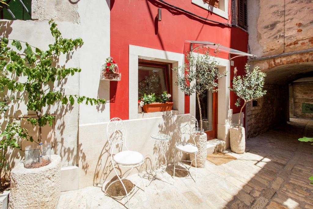grupa krzeseł i stołów przed budynkiem w obiekcie Apartments Villa Markiz w Rovinj