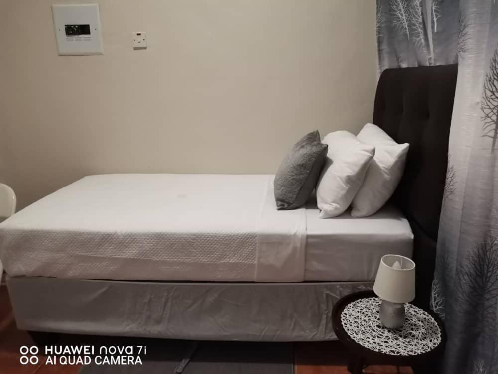 1 cama con sábanas blancas y almohadas en una habitación en Fabulous Rest Inn, en Francistown