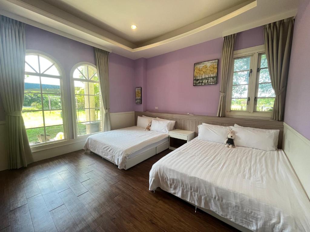 two beds in a room with purple walls and windows at 伊莎愛莉溜滑梯親子民宿 in Wujie