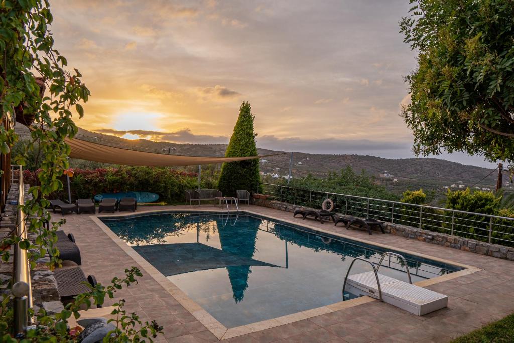 einen Pool mit Sonnenuntergang im Hintergrund in der Unterkunft Villa Gaia in Mílatos