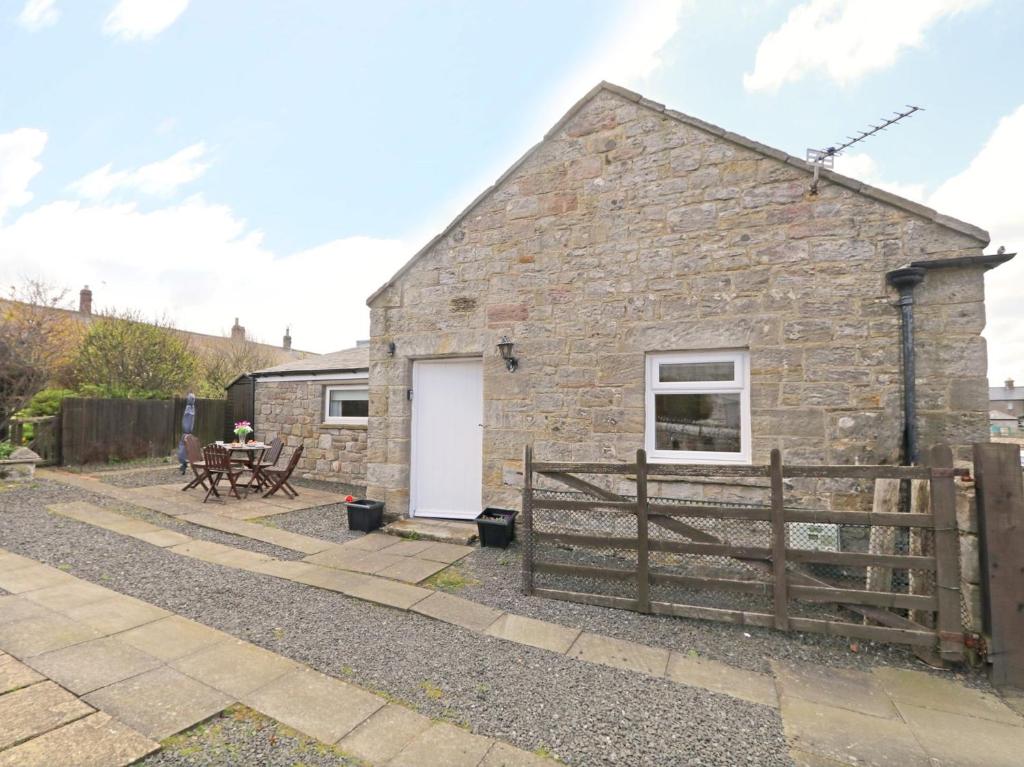 a stone cottage with a white door and a fence at 1 Bed in Boulmer 60516 in Boulmer