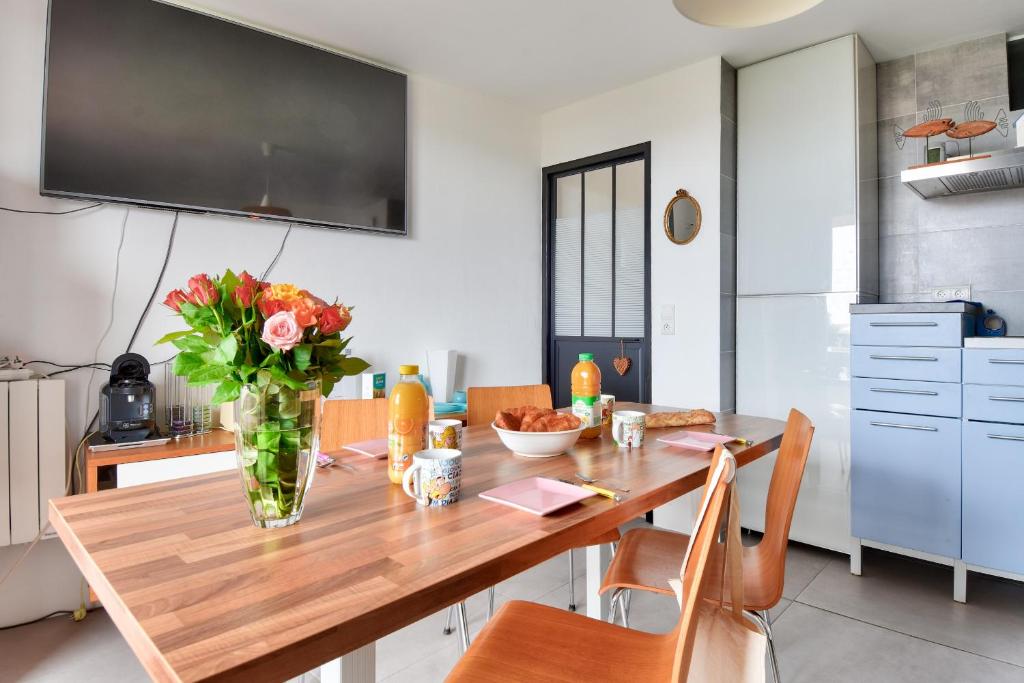 a dining room table with a vase of flowers on it at Douce echappee a Noirmoutier-en-l ile in Noirmoutier-en-l'lle