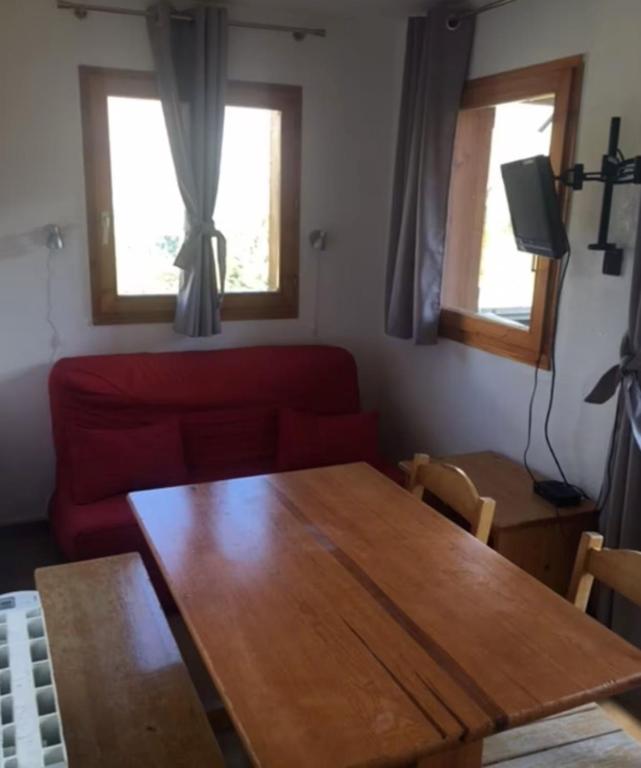 - un salon avec une table en bois et un canapé rouge dans l'établissement Apartment with 6 bed close to the slopes, à Saint-Étienne-en-Dévoluy