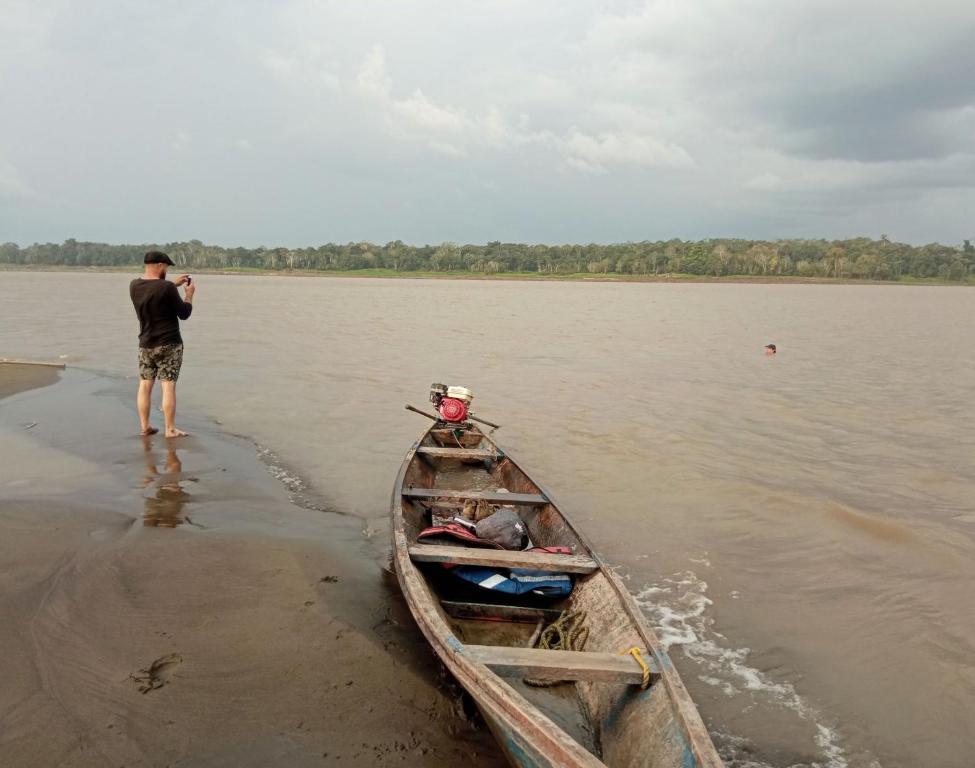 a man taking a picture of a boat on the shore at Hostal Búho Amazonas tours in Leticia