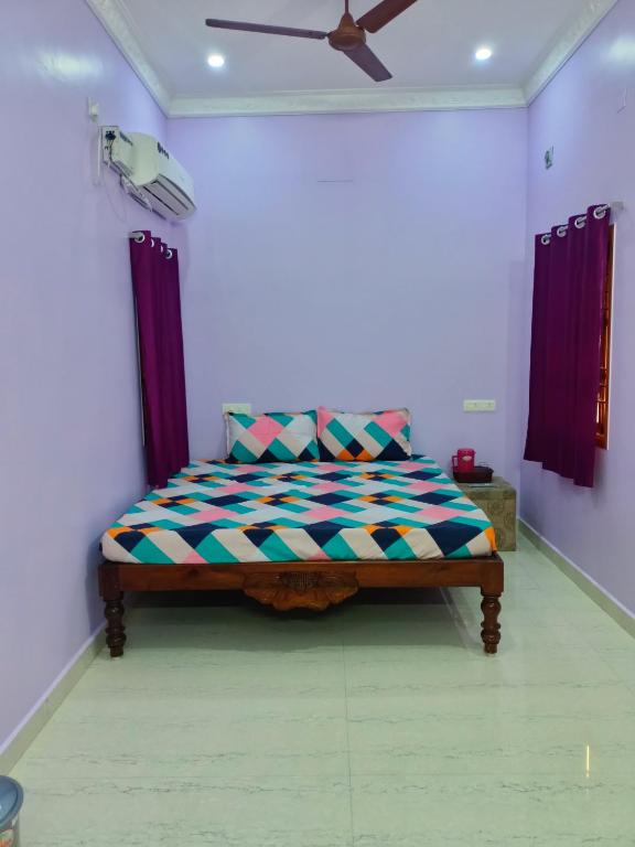 a bed in a room with a ceiling fan at VJ VILLA HOME STAY PURPLE ROOM in Puducherry