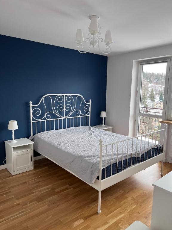 - une chambre dotée d'un lit avec un mur bleu dans l'établissement Krynica Zdrój Apartament 4 pokoje, à Krynica-Zdrój