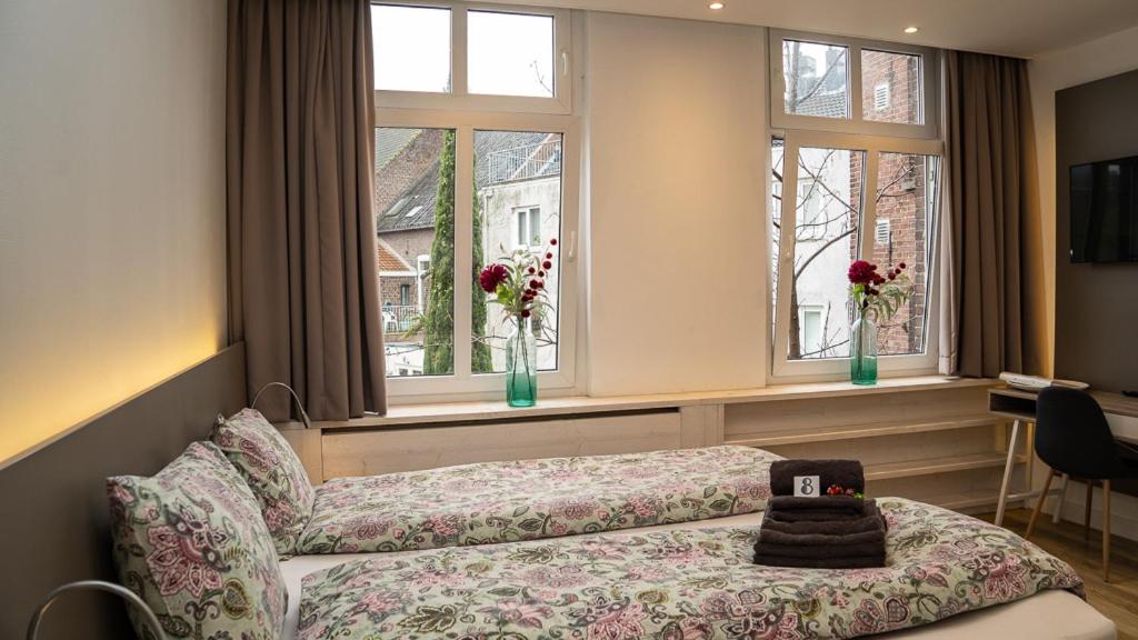 フェンロにあるInn den Acht Venloのソファと2つの窓が備わる客室です。