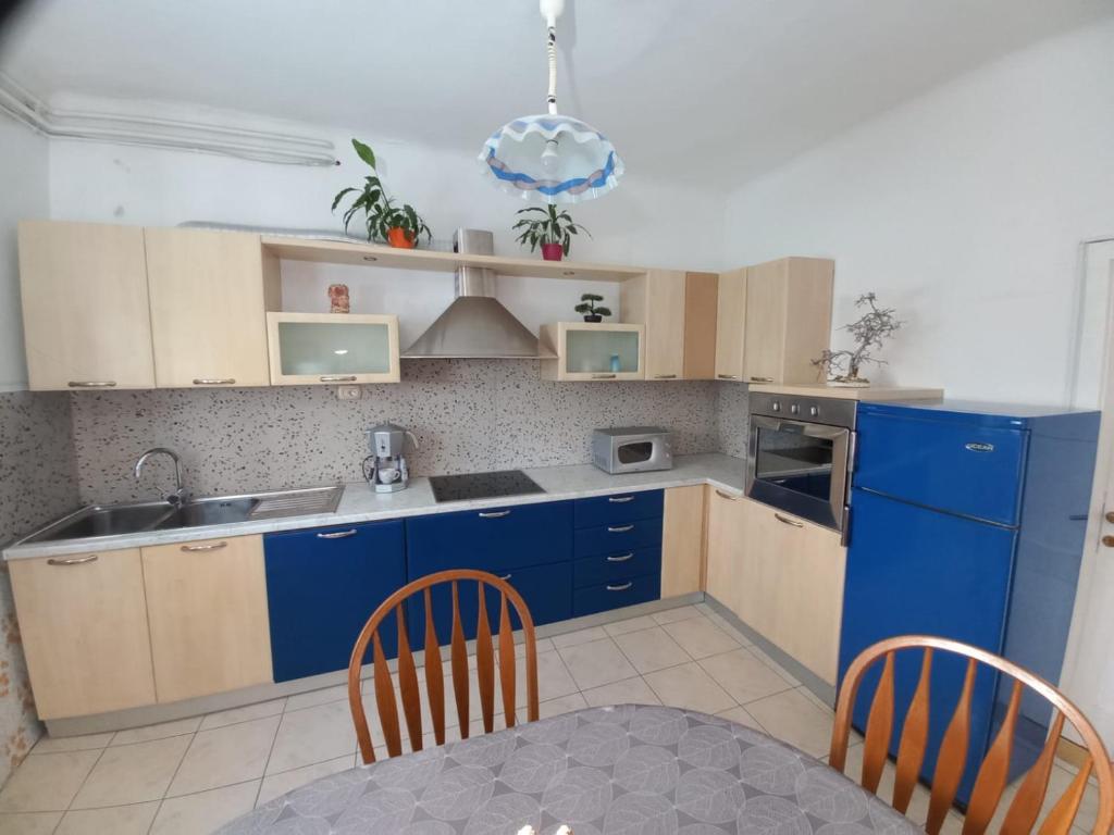 eine Küche mit blauen Schränken sowie einem Tisch und Stühlen in der Unterkunft Casa Crevatini in Koper