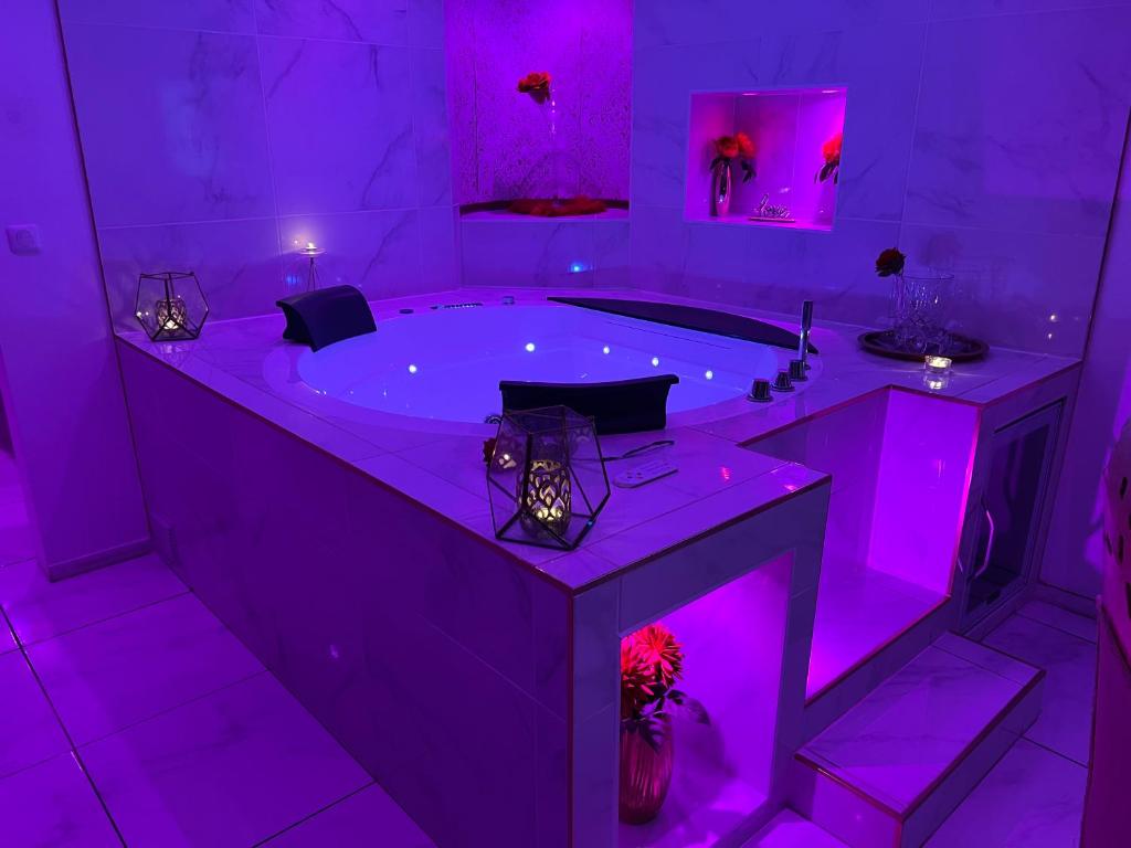 d'une salle de bains pourpre avec une grande baignoire à éclairage violet. dans l'établissement Suite romantique avec jaccuzy à la gare de Montpellier, à Montpellier